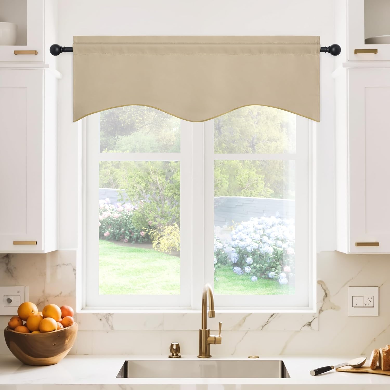 Beige fabric window valance with a scalloped edge, hung on a black rod above a kitchen window.