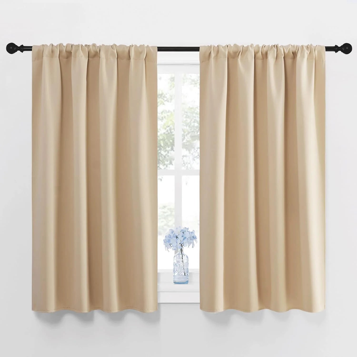 Pair of beige rod pocket short curtains on black rod over window.