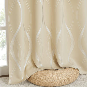 Beige curtain with shimmering silver wavy lines, draped over a woven pouf by a window.