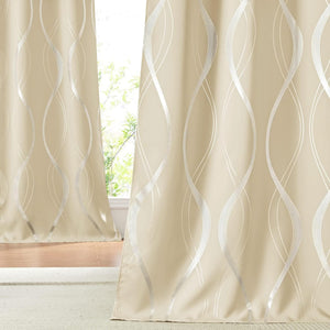 Modern beige window curtains with shimmering silver wavy patterns hanging in a bright room.