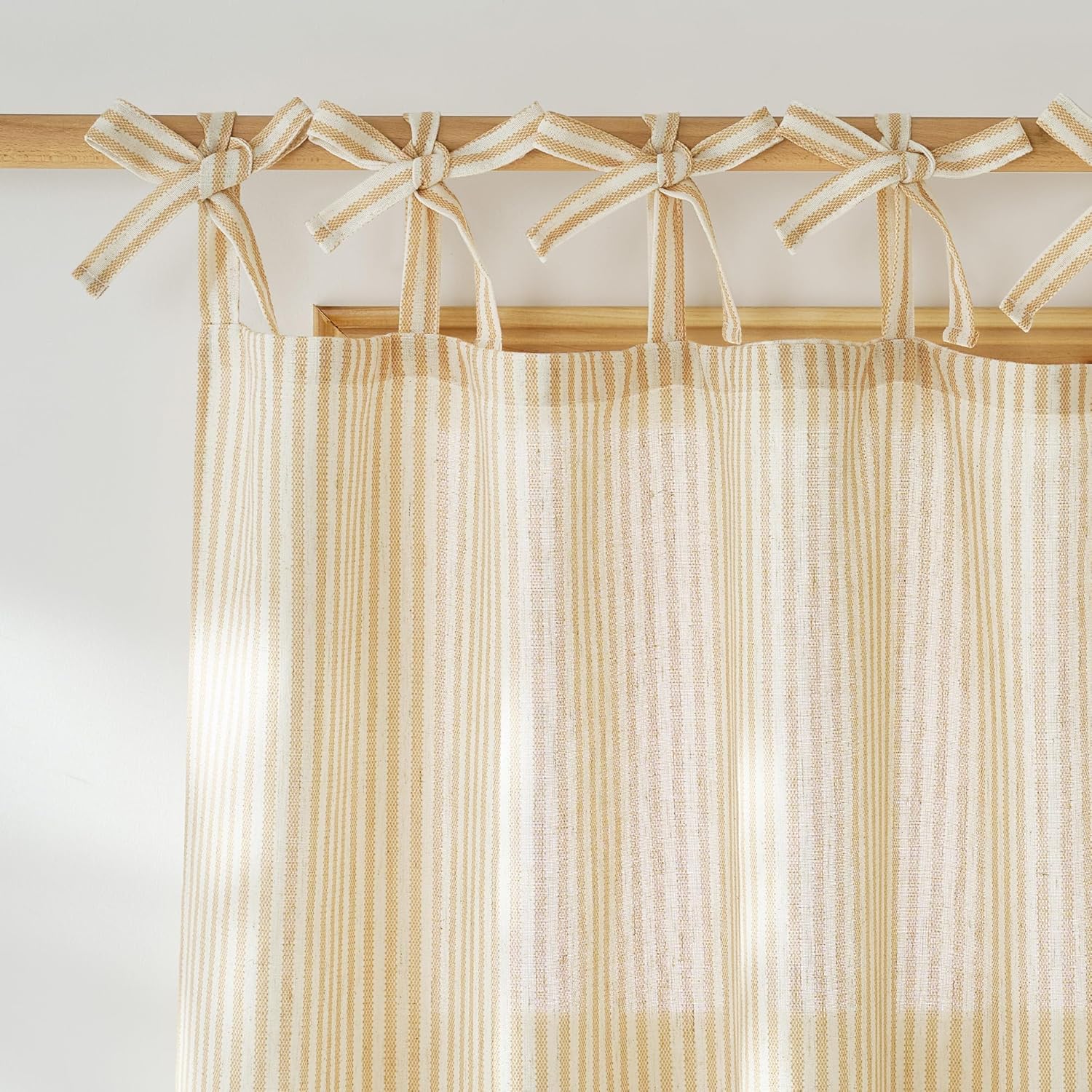 Beige and cream striped tie-top curtain panel with visible textured fabric, hanging on wooden rod.