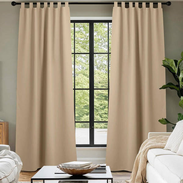 Beige tab top blackout curtains hang from a black rod, covering a modern living room window.