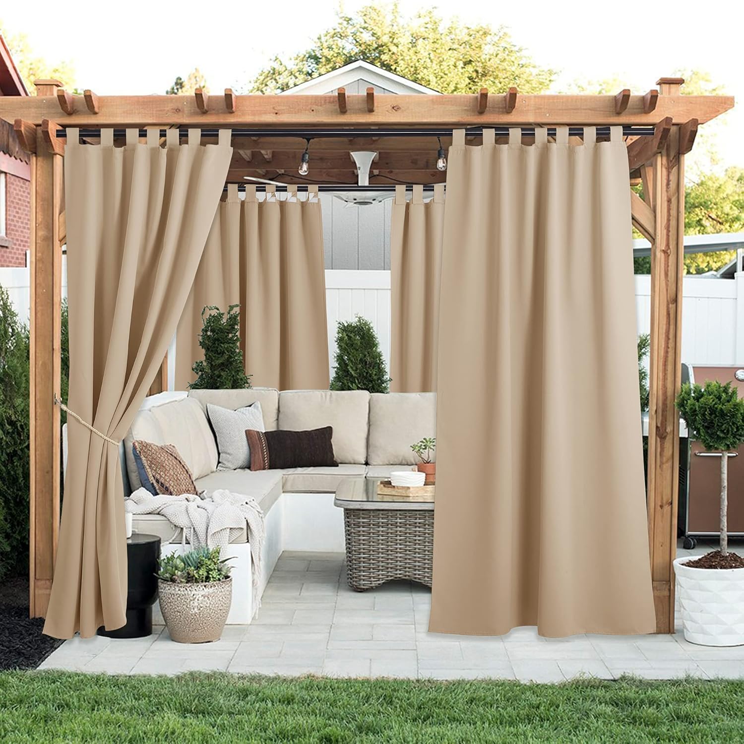 Beige tab top outdoor curtains on a pergola, providing privacy and shade for patio seating.