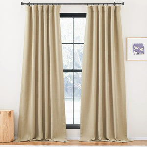 A pair of full-length beige textured pinch pleat curtains hangs on a black rod, framing a modern window.