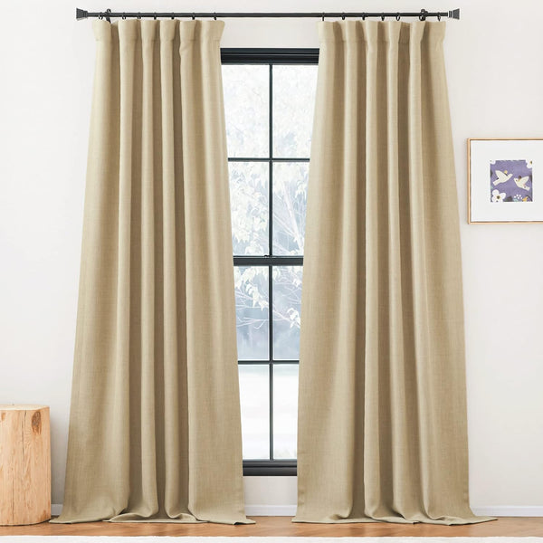 A pair of full-length beige textured pinch pleat curtains hangs on a black rod, framing a modern window.