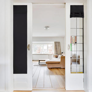Black blackout fabric panels on white glass interior doors, one extended, one rolled.
