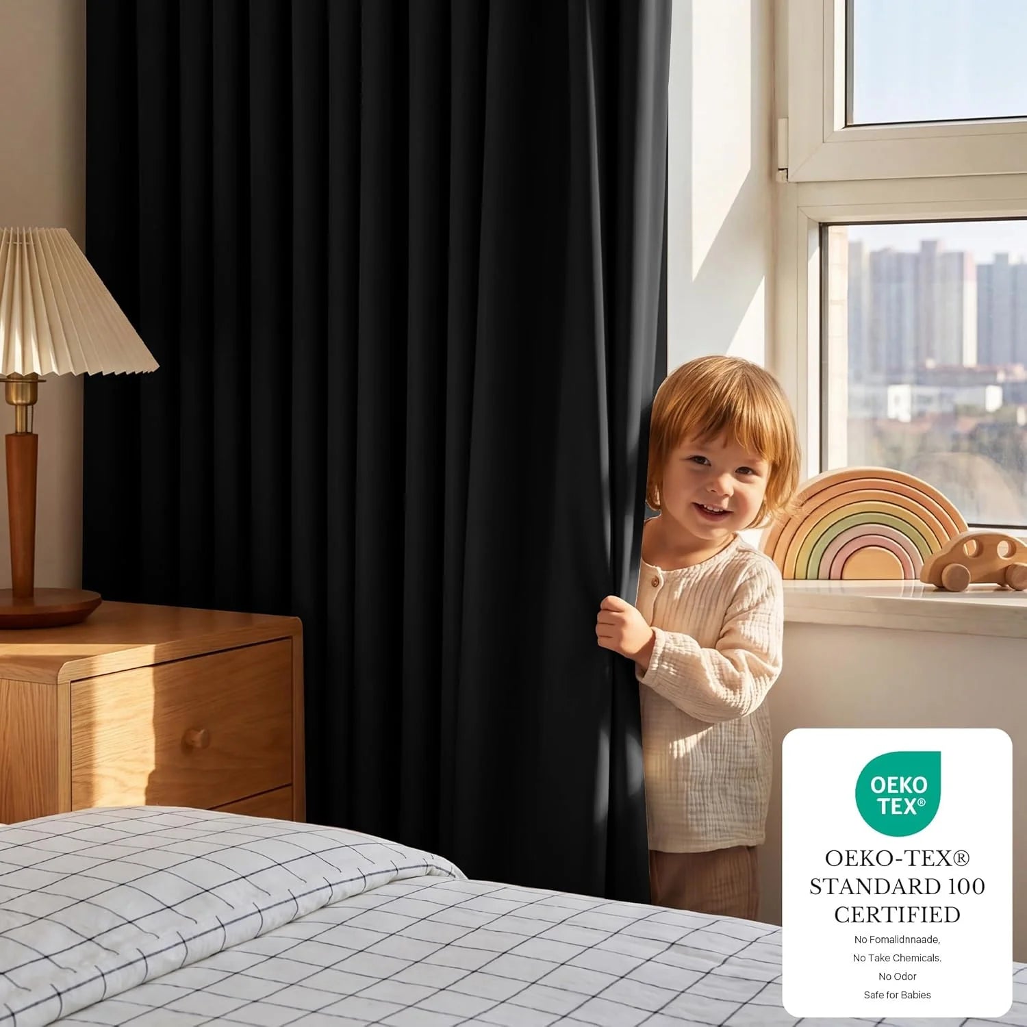 Smiling child peeks from black blackout curtain in a modern bedroom, OEKO-TEX certified.