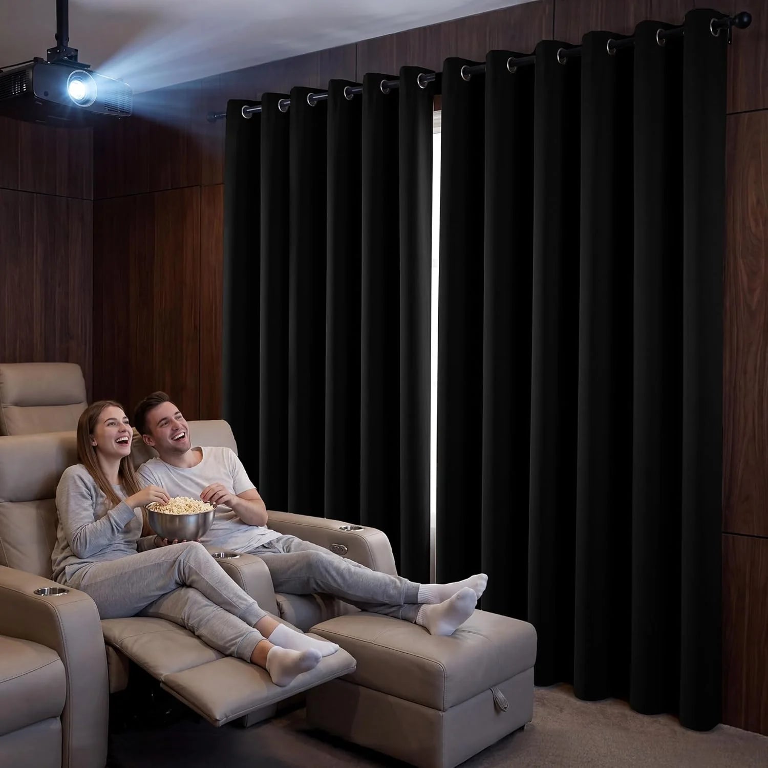 Couple watching a movie in home theater with black blackout grommet curtains