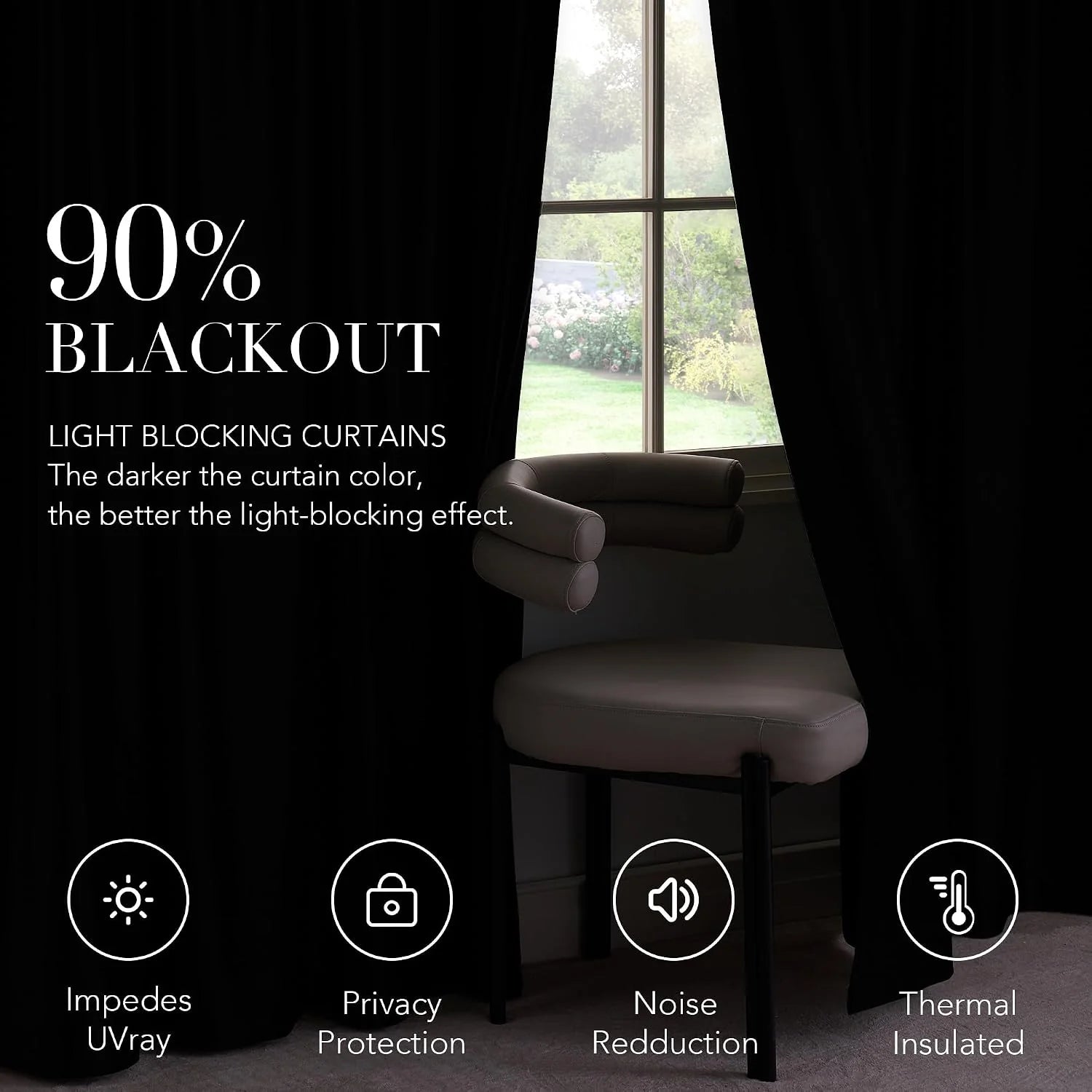 Black blackout curtains framing a tall window beside a modern upholstered chair