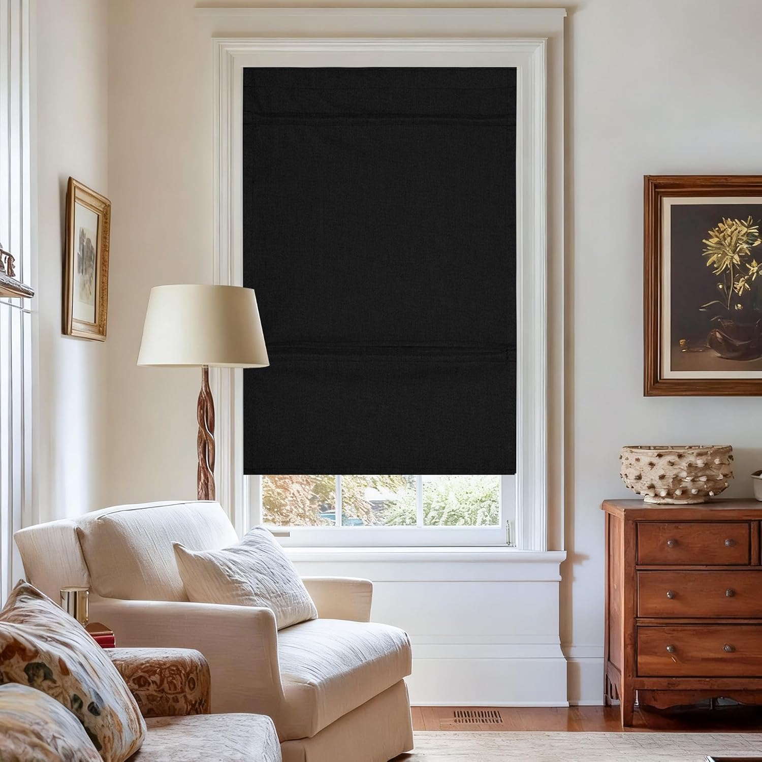Black fabric Roman blind providing full blackout on a window in a bright living room.