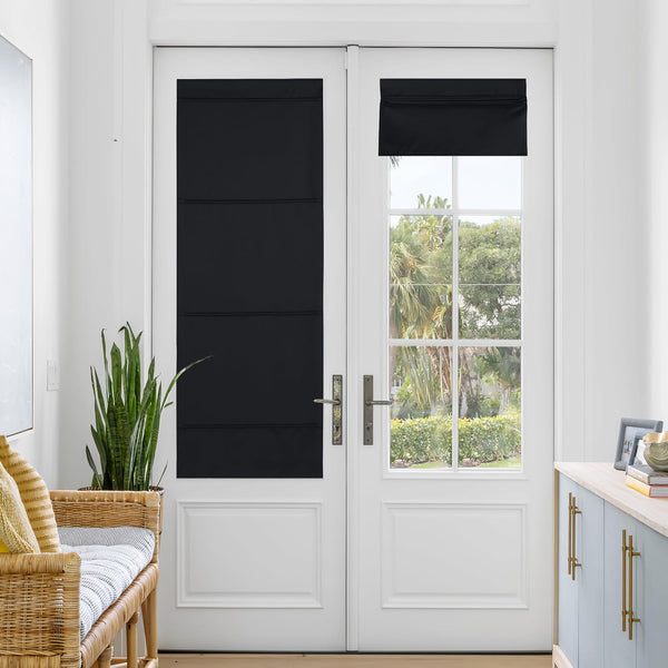 Black blackout flat roman shades installed on glass panels of white French doors, one fully closed, one partially open.