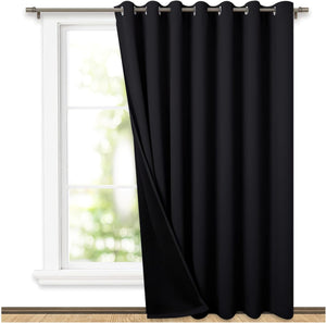 Black grommet top blackout curtain panel hanging on a window rod, partially open.