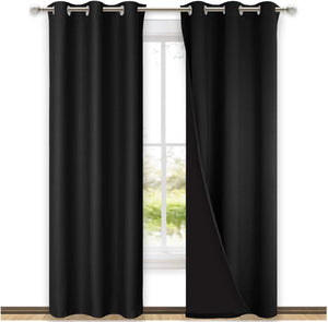 Black blackout grommet curtains hanging on a rod over a window. One panel is open, showing the thick fabric.