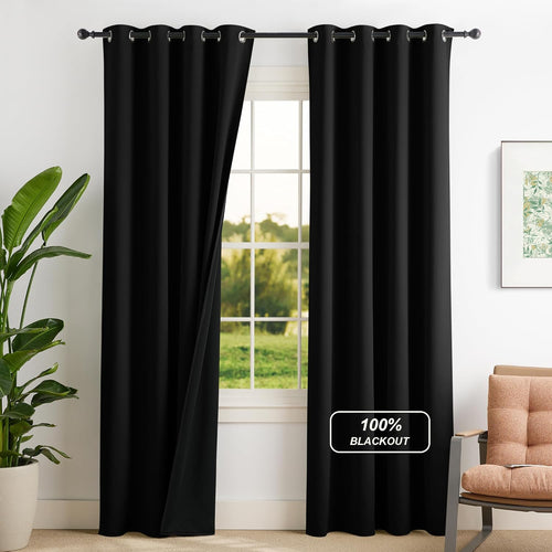Black 100% blackout curtains with silver grommet tops hang on a window, one panel slightly open.