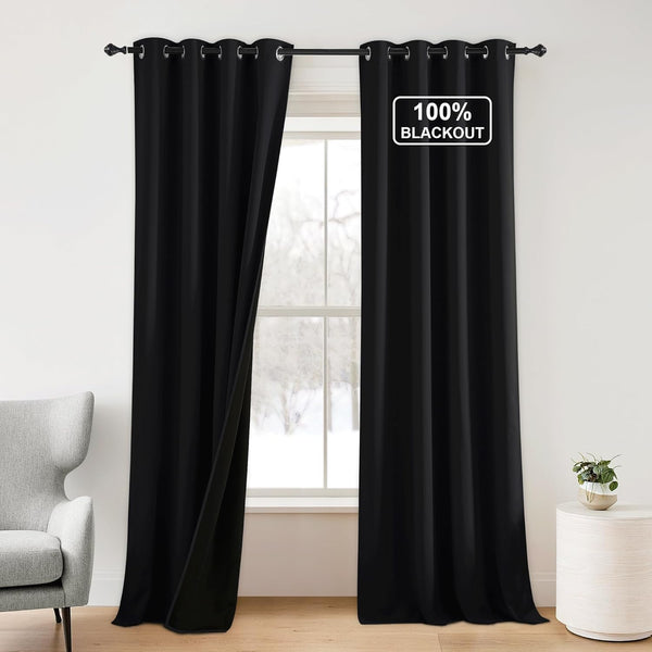 Solid black 100% blackout curtains with grommet top, one panel slightly open, hangs on a window rod.
