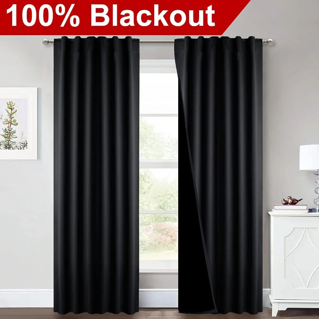 Black 100% blackout grommet curtains hanging over a bright window in a modern room