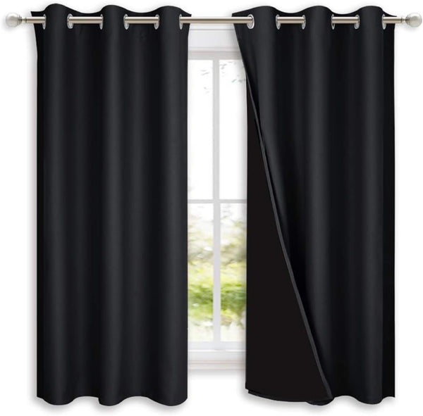 Black blackout curtains with silver grommet tops on a rod, one pulled back showing opaque lining.