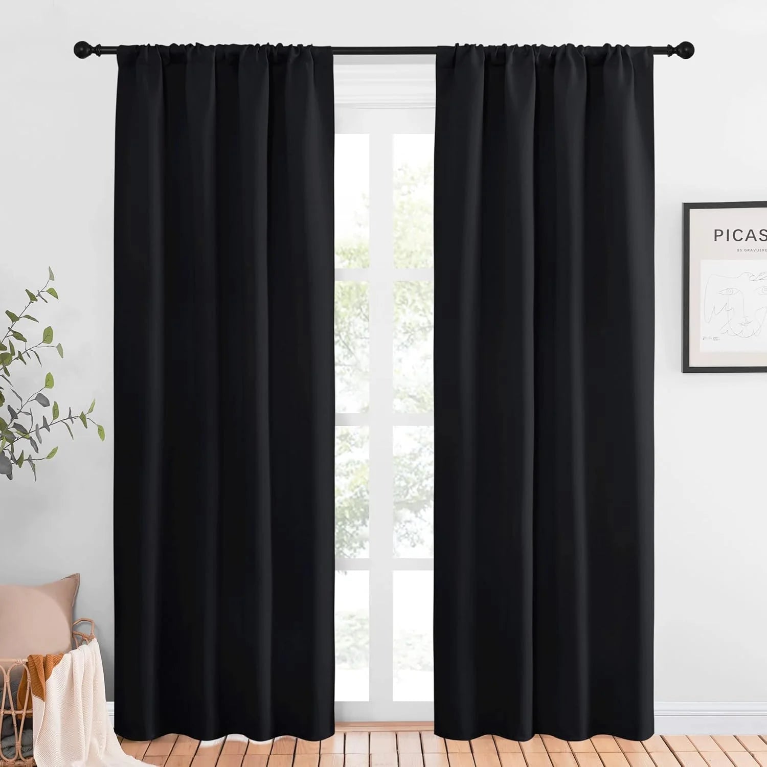 Black blackout curtains with rod pocket top hanging on a black curtain rod
