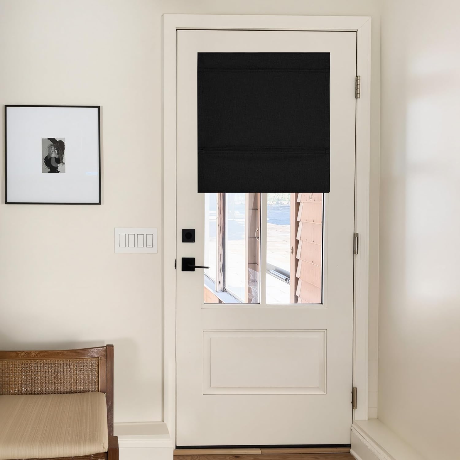 Black fabric roman blackout shade installed on a white entry door window, creating privacy.