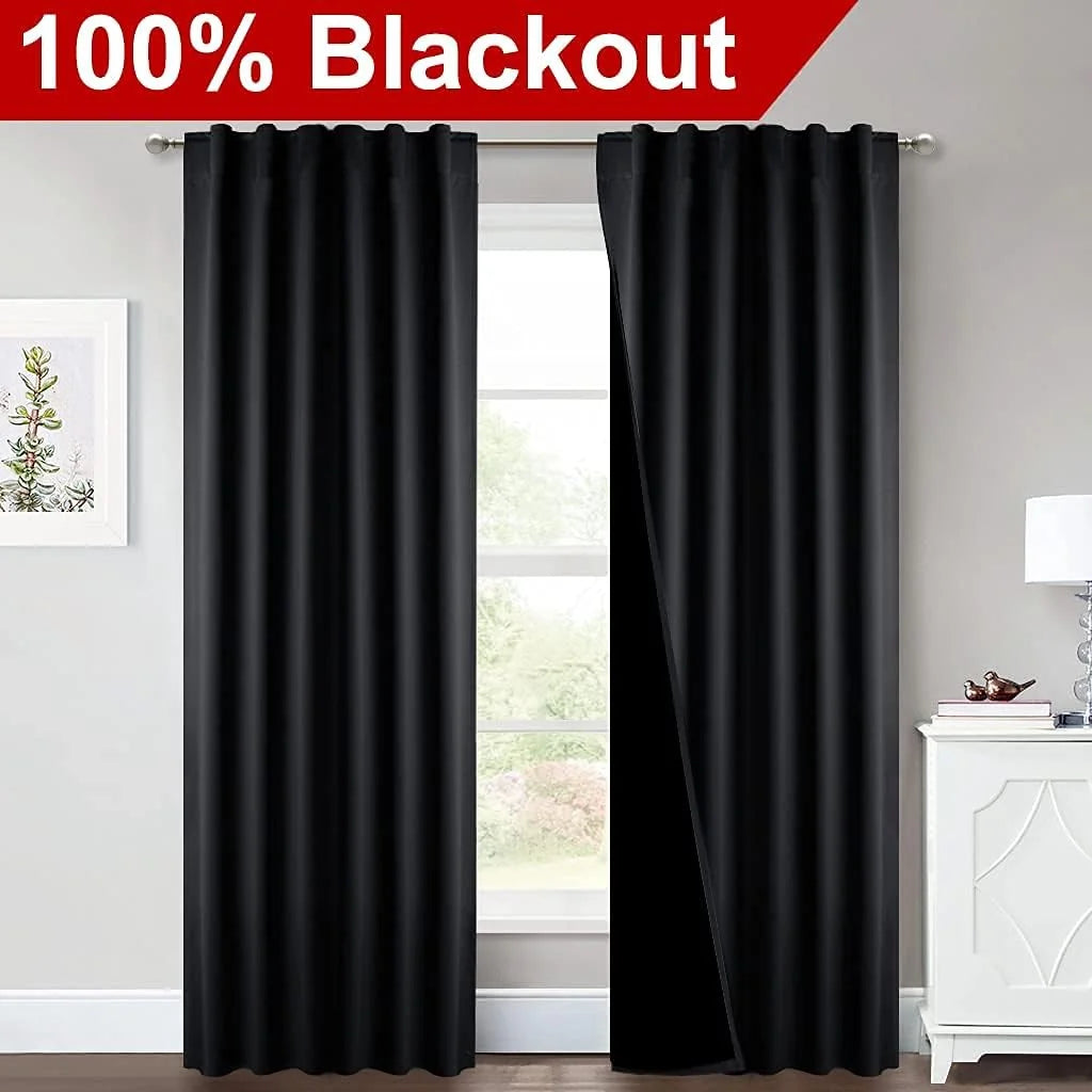 Black blackout curtains on a silver rod in a bright modern room window