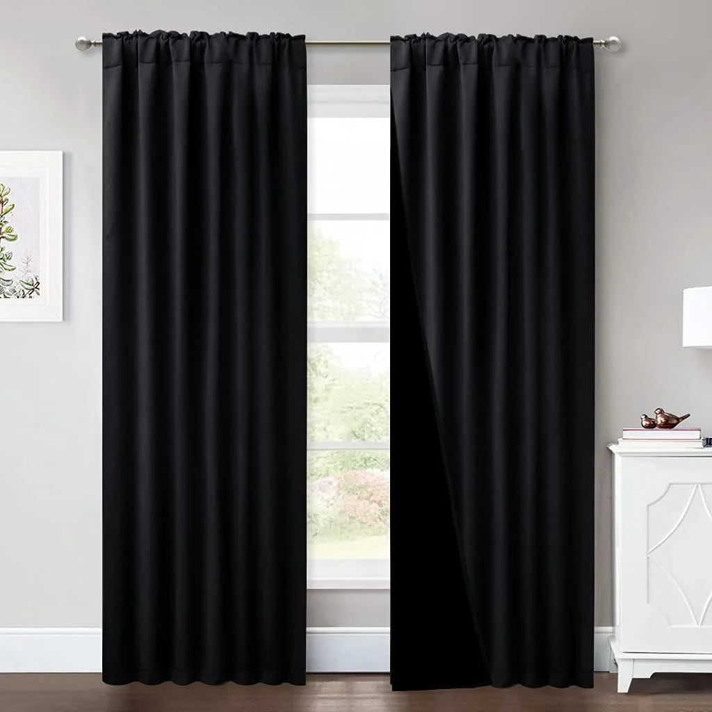 Black blackout curtains with rod pocket top hanging in a modern neutral room