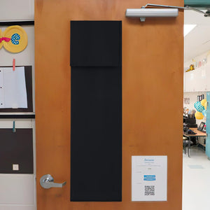 Long black fabric privacy door cover hangs vertically on a light brown wooden classroom door, providing instant privacy.