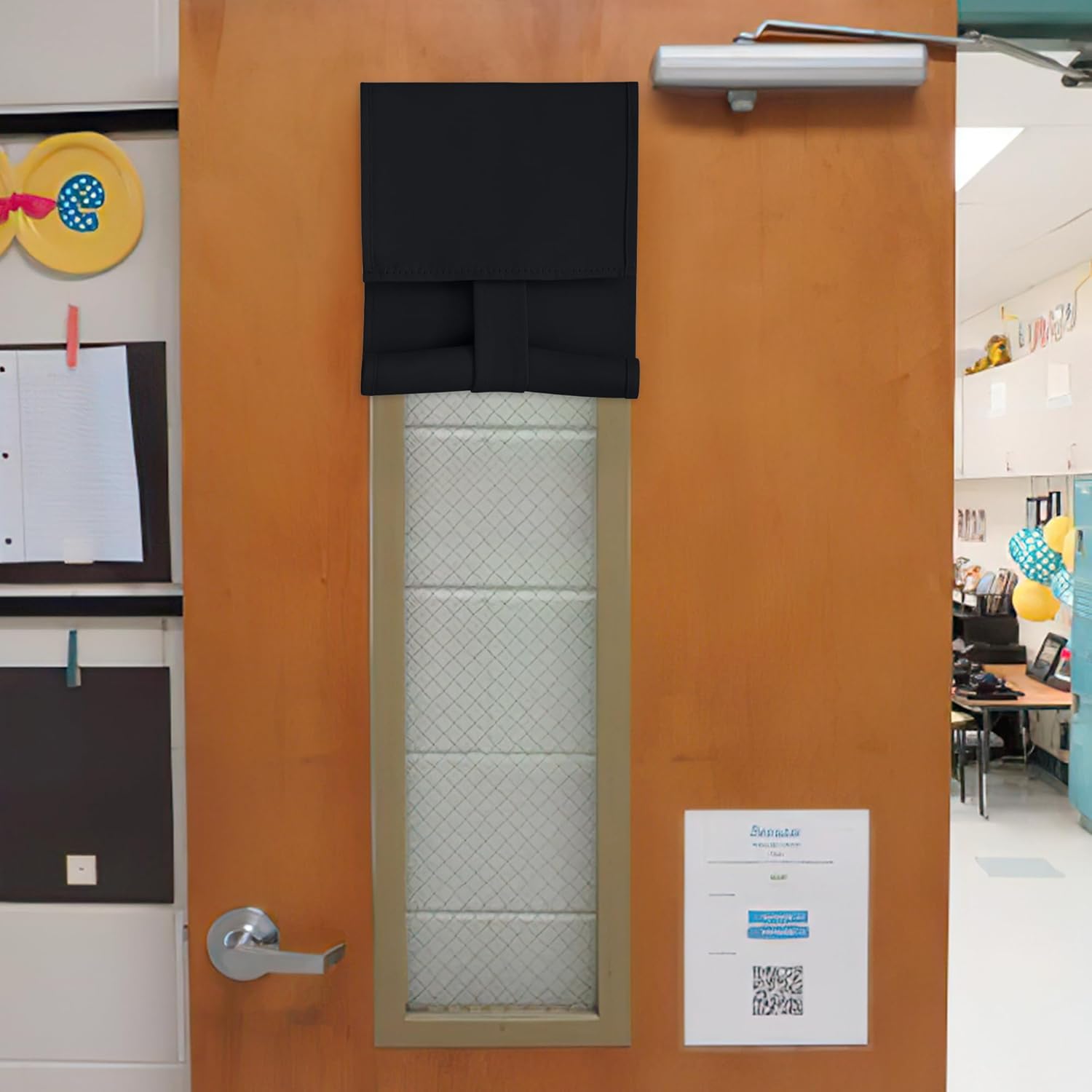Black fabric door window cover rolled up on a wooden door, revealing a security glass window with a grid.