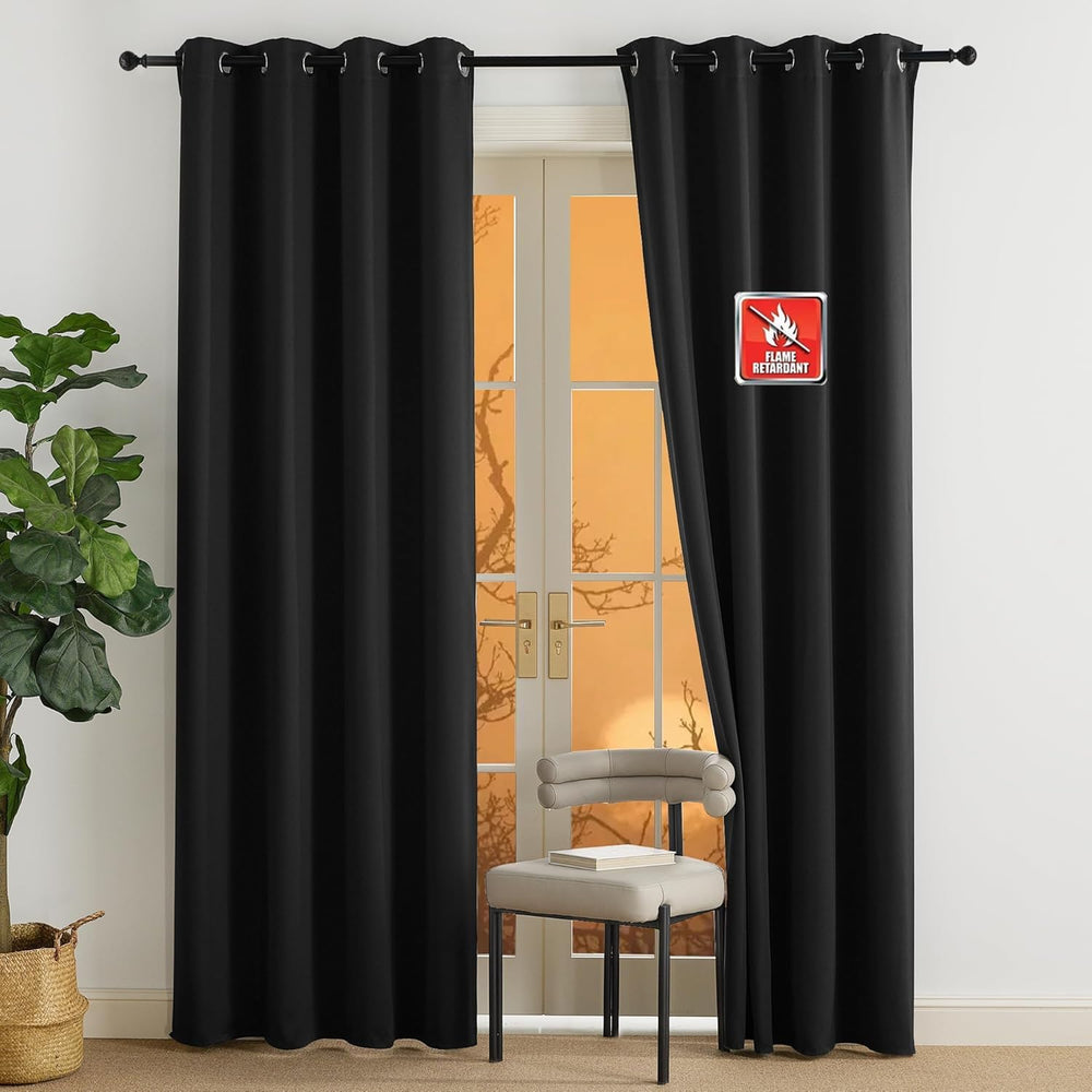Solid black flame retardant blackout curtains with silver grommets, hanging over a glass door.