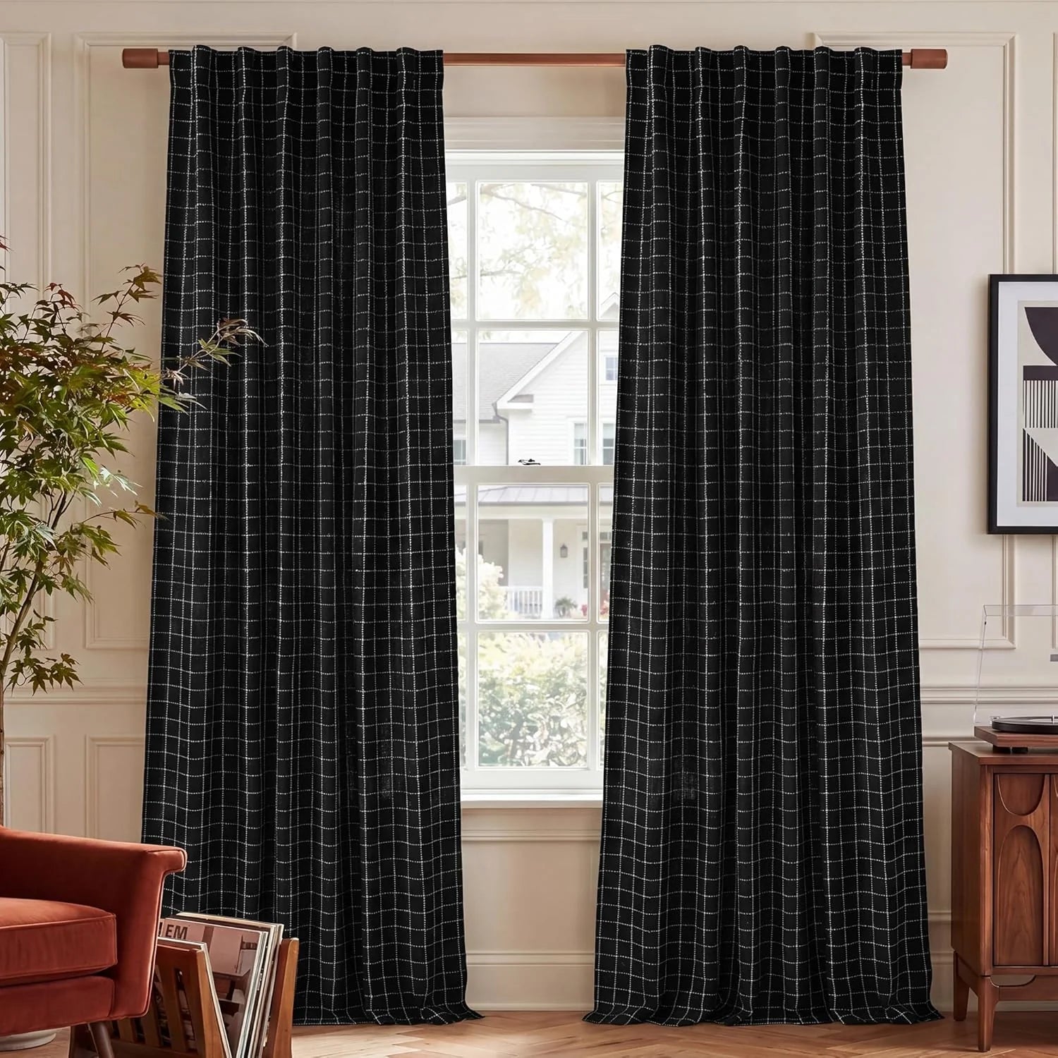 Black window curtains with a white grid pattern on a wooden rod in a warm living room.