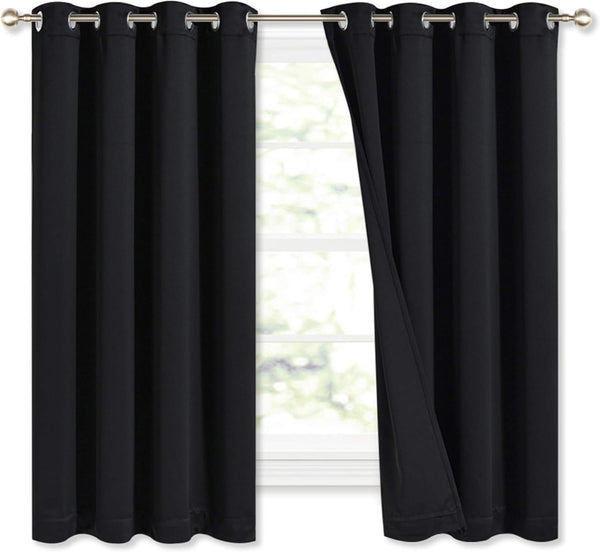 Pair of black blackout curtains with silver grommet tops on a window rod. One panel is slightly open.