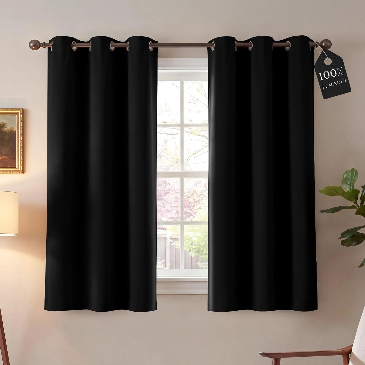 Black grommet blackout curtains on a rod over a window, '100% Blackout' tag visible.