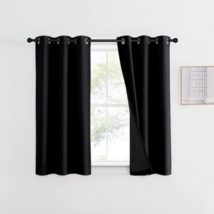 Pair of black grommet blackout curtains hanging on a rod above a window in a white room