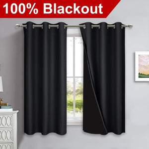 Pair of black blackout curtains with silver grommet tops hanging on a rod. One curtain slightly open.