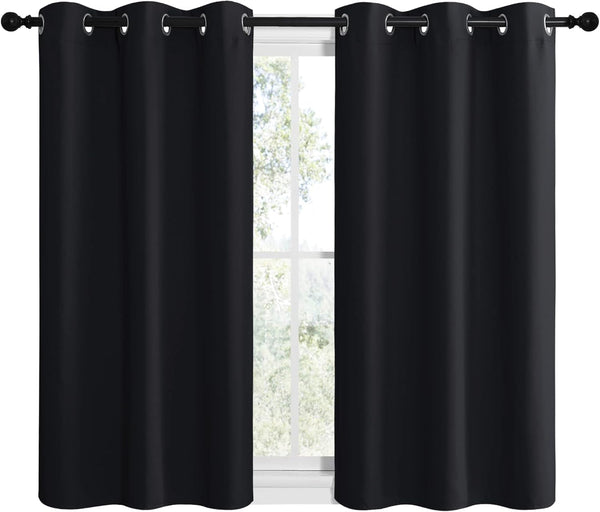 Pair of solid black blackout curtains with silver grommet tops on a window rod.