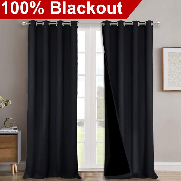 Thick black blackout curtains with silver grommet tops, showing dark lining, hanging over a white French door.