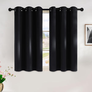 Two black blackout curtains with silver grommet tops hanging on a black rod over a window.