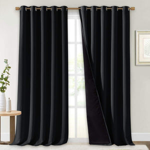 Black blackout grommet curtains hanging on a rod. One panel is slightly open, showing the thick, dark lining.