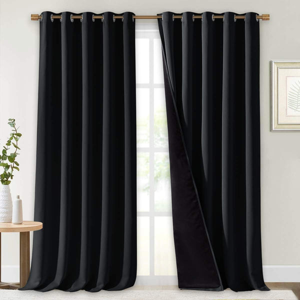 Black blackout grommet curtains hanging on a rod. One panel is slightly open, showing the thick, dark lining.