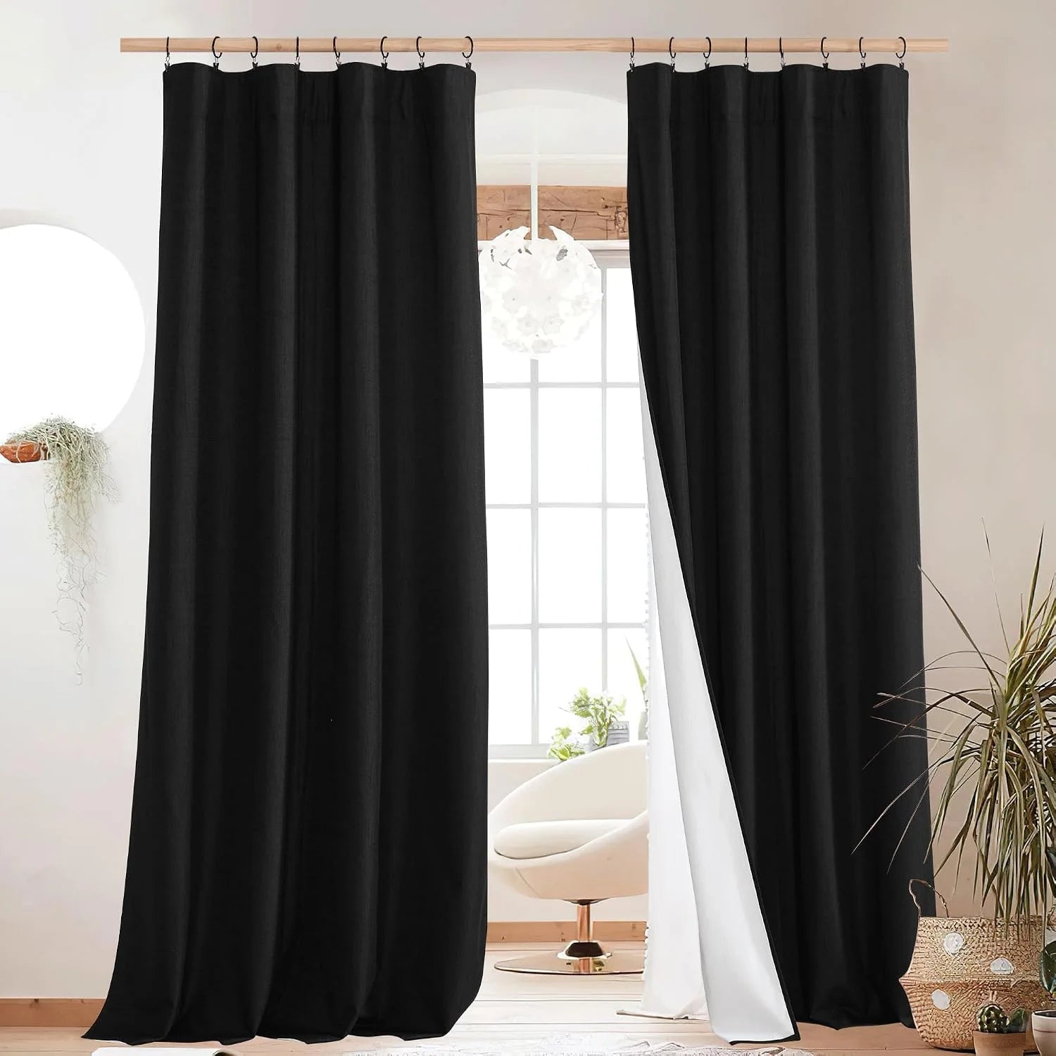 Black linen-look curtains on rings framing a bright window in a modern room