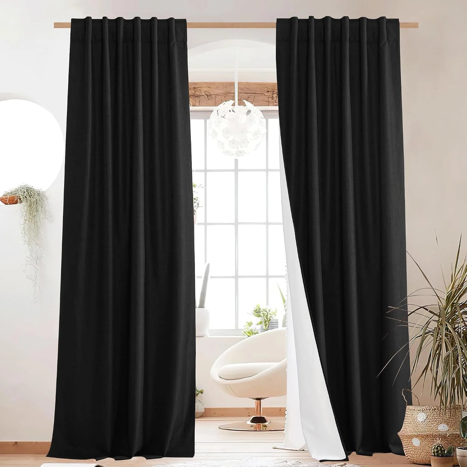 Black linen-look rod pocket curtains framing a bright window in a modern room