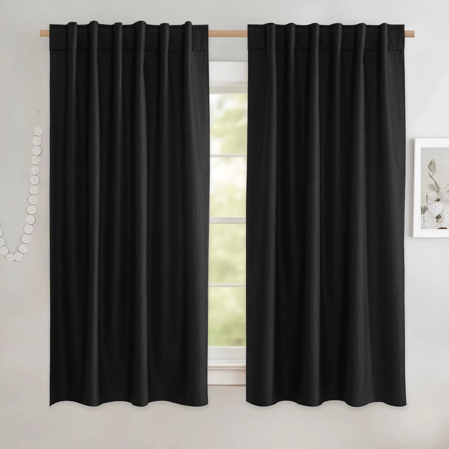 Black linen-look rod pocket curtains hanging on a light wood curtain rod