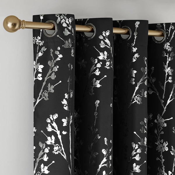 Black curtains with metallic silver floral branch pattern and shiny grommet tops on a gold rod