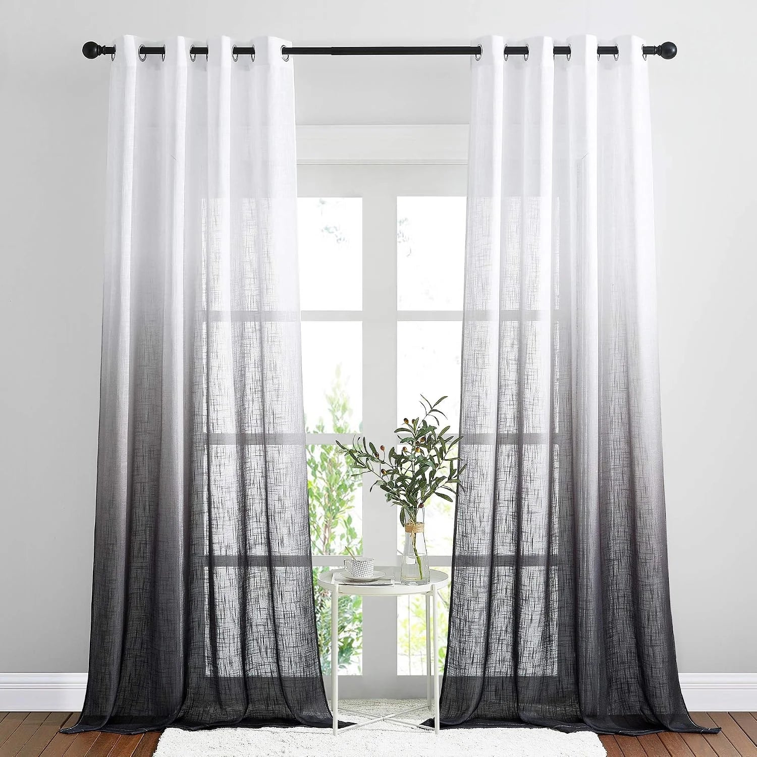 White to black ombre sheer curtains with grommet top hanging in a bright window