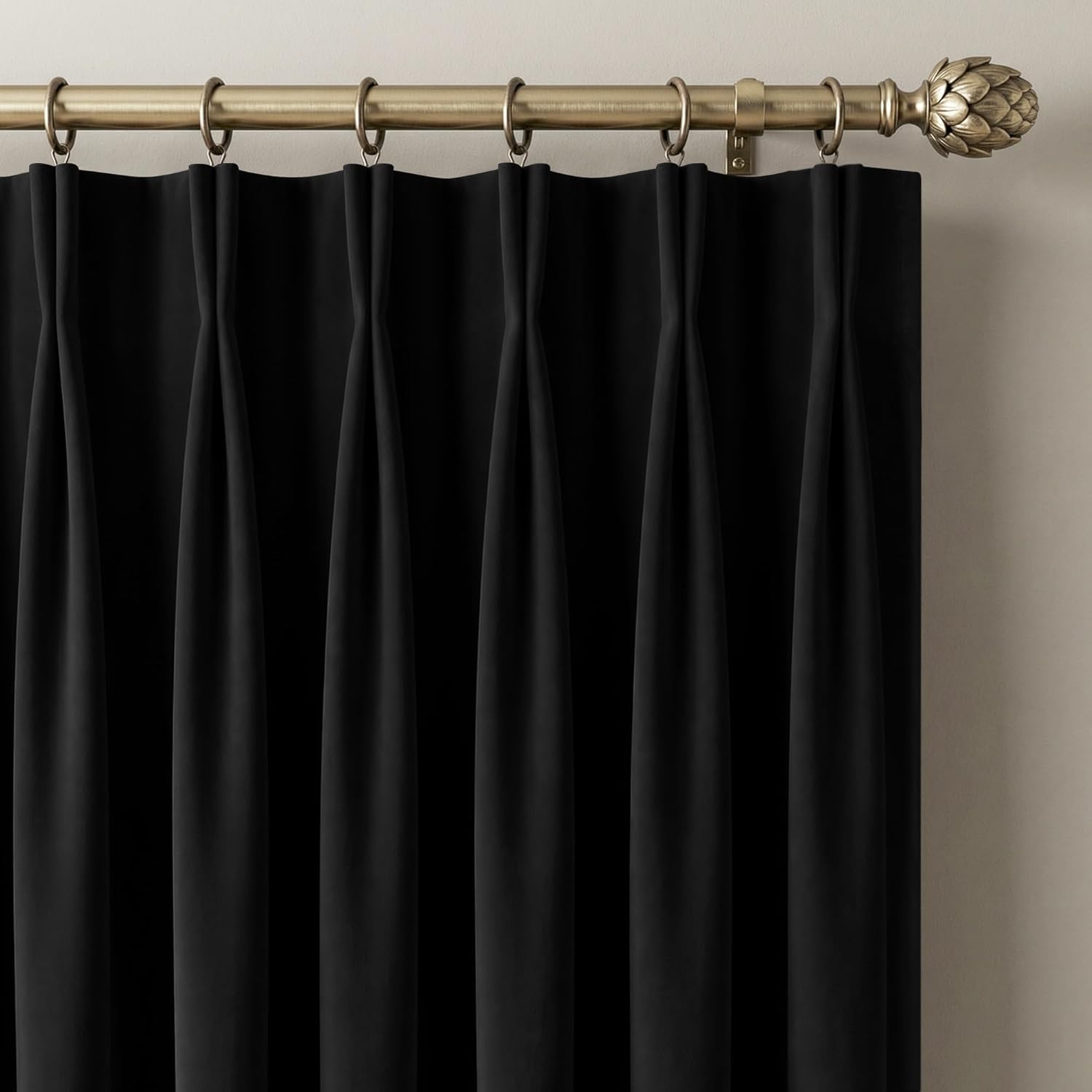 Black pinch pleat curtain panel on an antique brass rod with a detailed artichoke finial.