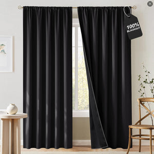 A pair of black rod pocket blackout curtains hanging on a gold rod over a window, one panel slightly open.