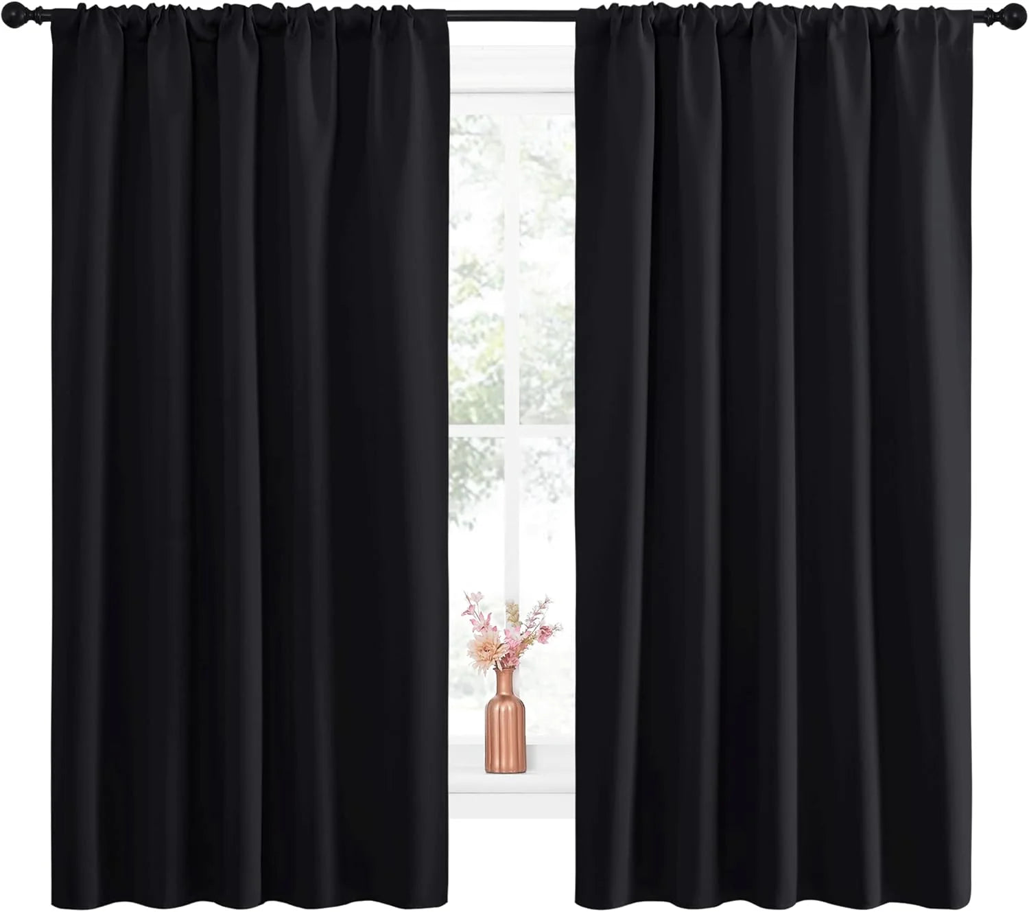 Pair of black rod pocket blackout curtains on a dark rod, framing a window with small floral vase.