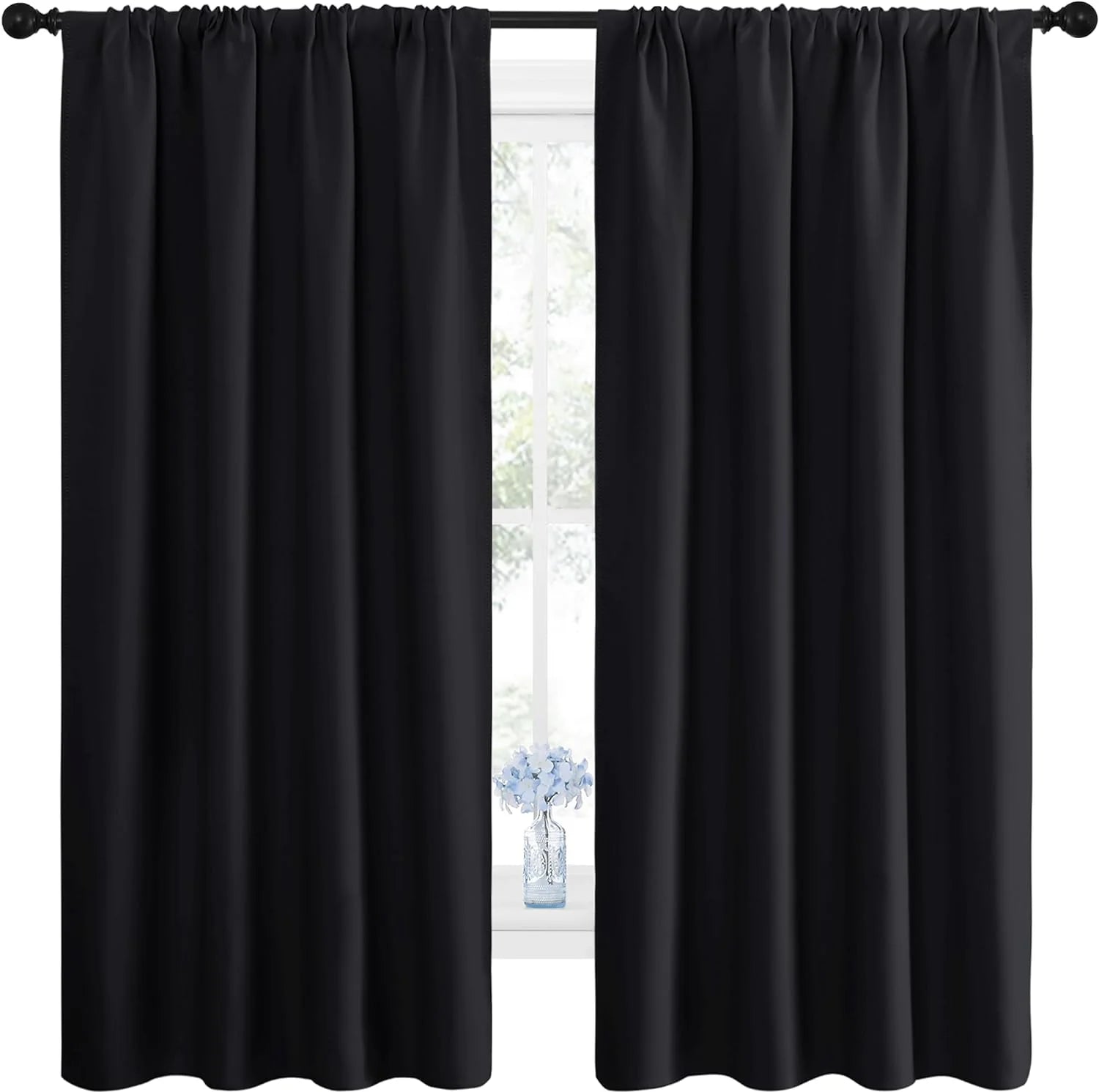 Two panels of solid black blackout curtains with a gathered rod pocket top, hanging over a window.