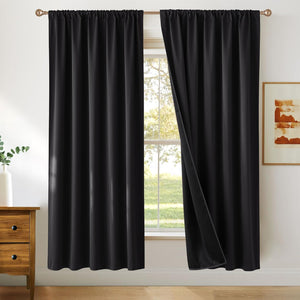 Two black solid blackout curtains with a rod pocket top, hanging on a bronze rod in a bright room.
