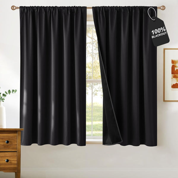 Black rod pocket blackout curtains. One panel open, showing opaque lining and '100% BLACKOUT' tag.