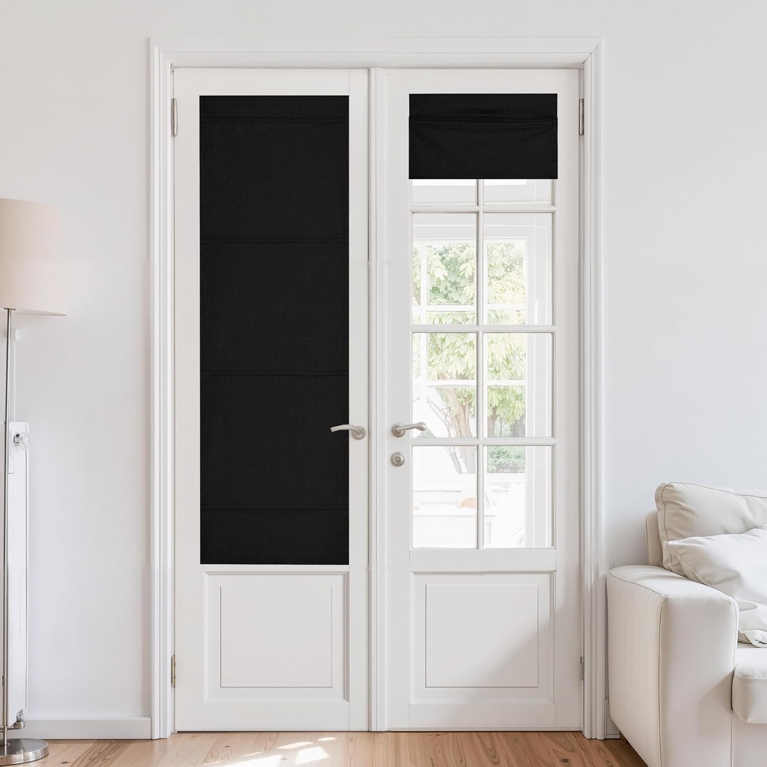 Black Roman blackout shades cover white French doors. One is down, one rolled up revealing outdoor view.